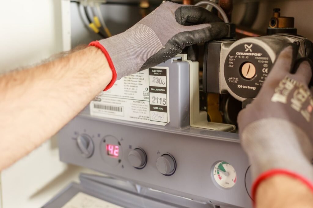 pexels-photo-7859953-7859953 Close-up of hands adjusting a boiler system with precise instrumentation, showing maintenance work.
